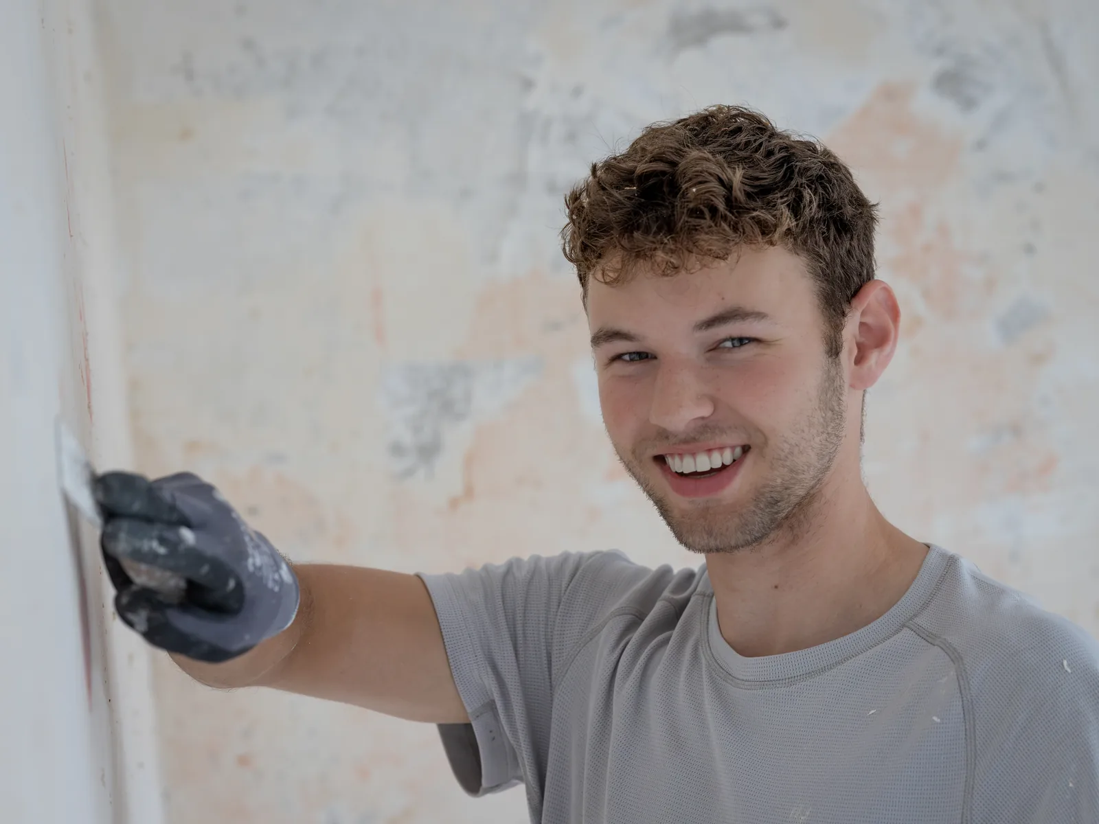 Mitarbeiter des Betriebs zieht Spachtelmasse mit der Glättkelle über eine Wand
