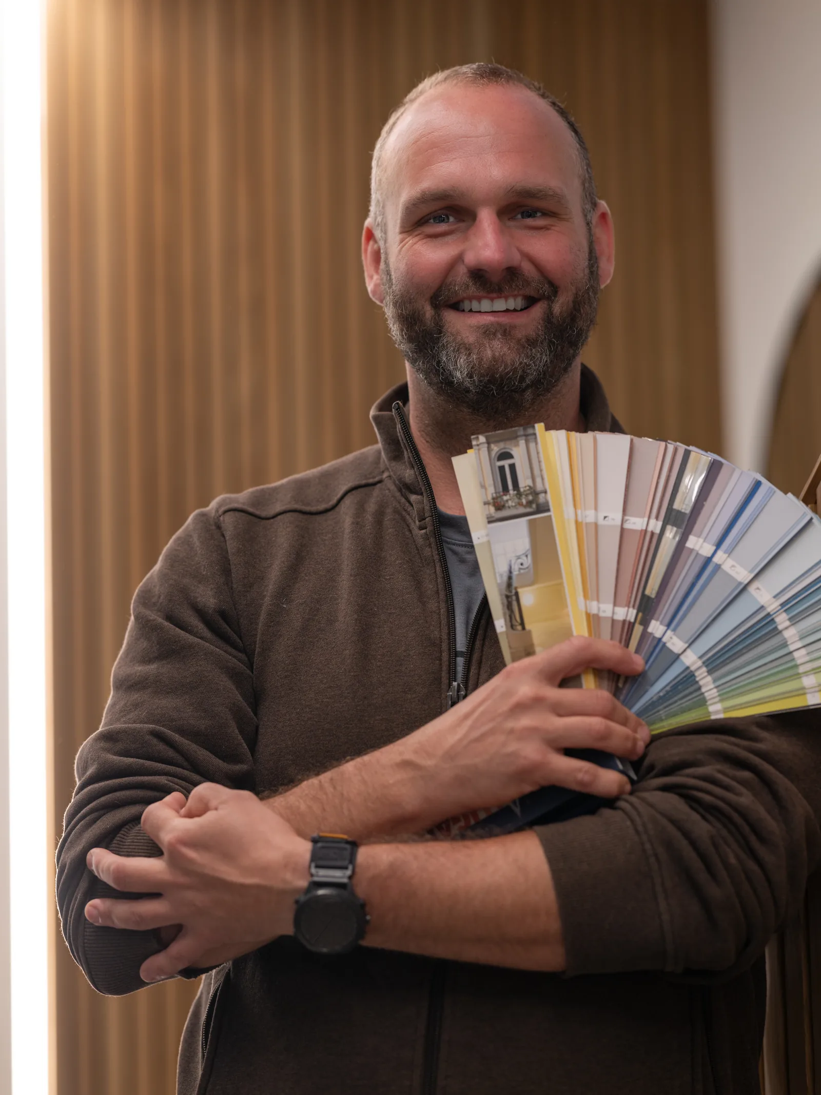 Marc Kamp, Malermeister, hält einen aufgefächerten Farbtonfächer in der Hand